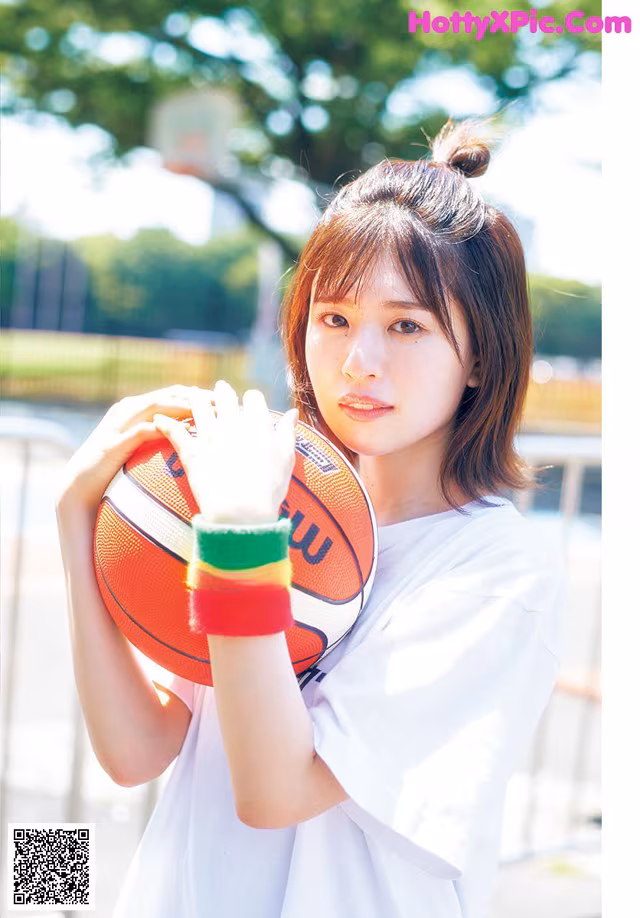A young woman holding a basketball in her hands.