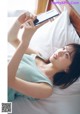 A woman laying in bed holding a cell phone.