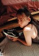 A young girl laying on the floor holding a pair of shoes.