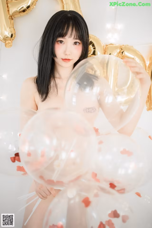A naked woman holding a bunch of balloons.