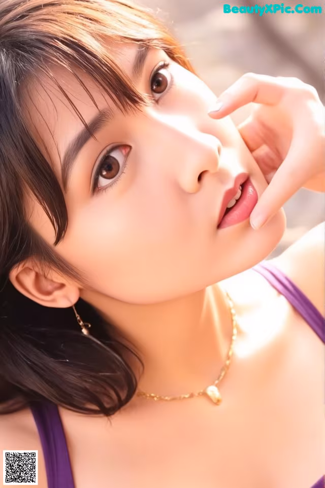 A woman wearing a purple tank top and a gold necklace.