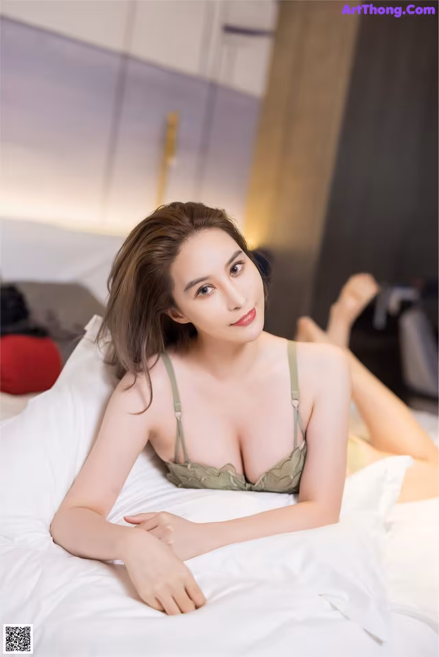 A woman laying on top of a bed in a green bra.