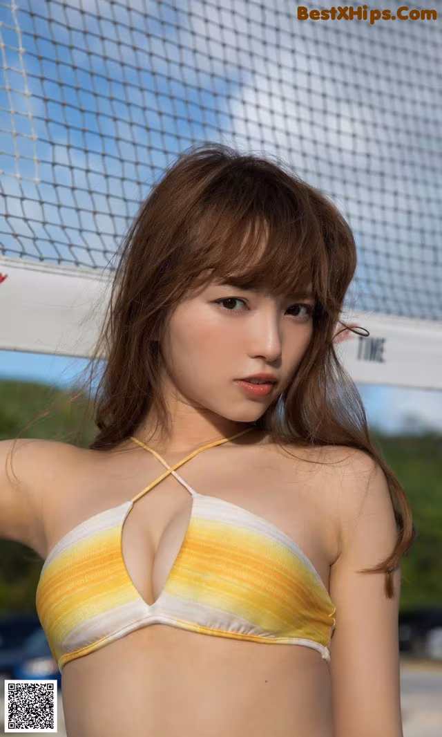 A woman in a yellow and white bikini posing for a picture.