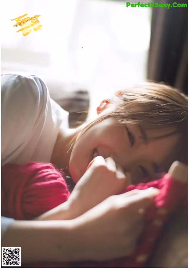 A woman laying on top of a bed next to a window.