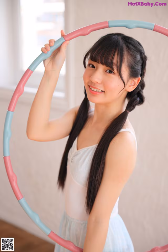 A young woman holding a hula hoop in her hands.