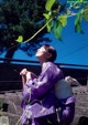 A woman in a purple kimono sitting on some steps.