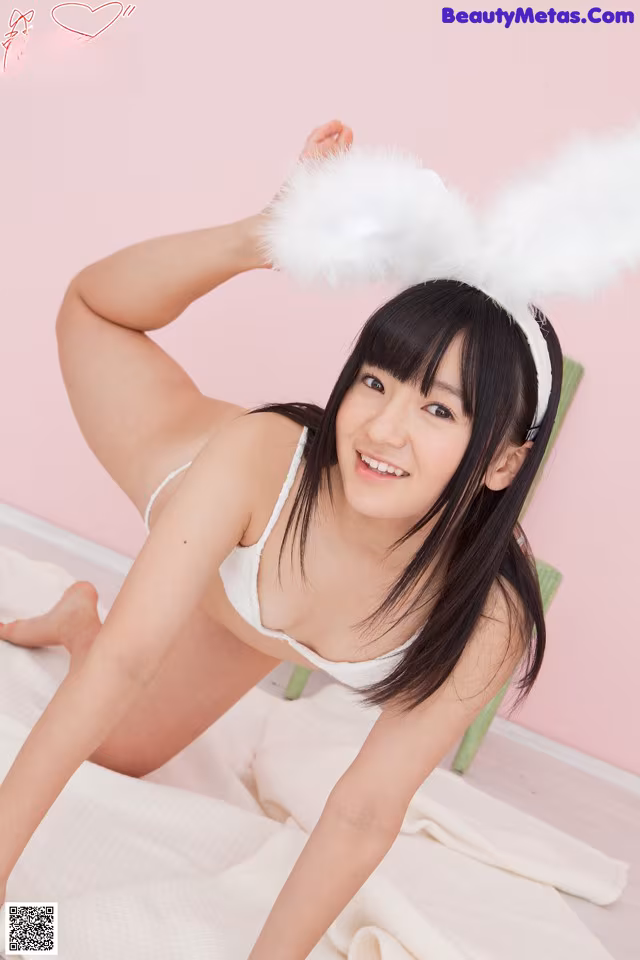 A woman in a white bunny costume posing on a bed.