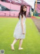 A woman in a striped dress standing on a baseball field.