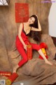 A woman in a red outfit sitting on a couch.