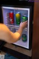 A person is opening a mini fridge with cans of beer.