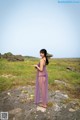 A woman in a purple dress standing on a rock.