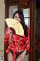 A woman in a red kimono holding a yellow fan.