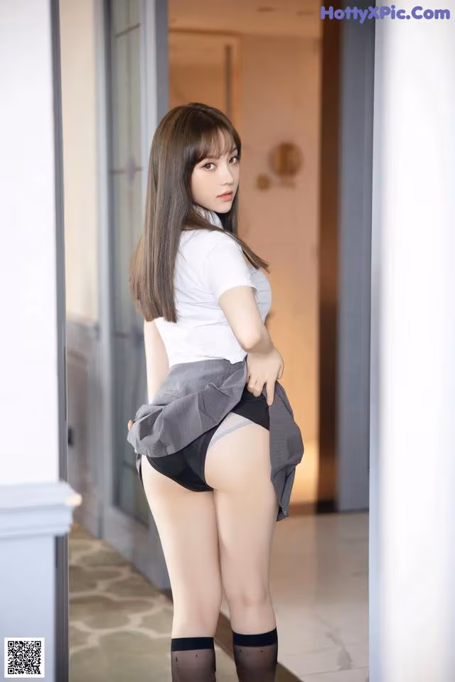 A woman in a white shirt and black skirt posing for a picture.