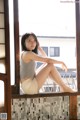 A woman sitting on a window sill with her legs crossed.