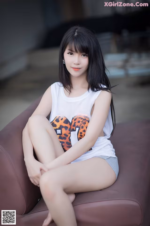 A woman sitting on top of a brown couch.